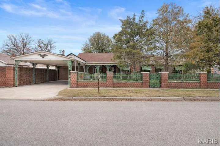 Ranch-style house with a fenced front yard, driveway, an attached carport, and brick siding