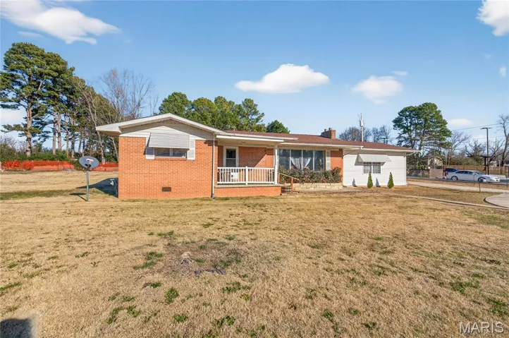 Ranch-style house featuring a front lawn, crawl space, brick siding, covered porch, and a chimney