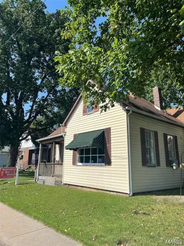 View of property exterior featuring a yard, a chimney, and a porch