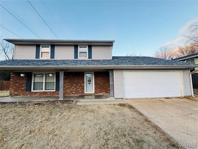 Traditional-style home with covered porch, an attached garage, driveway, and brick siding