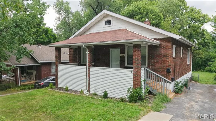 Bungalow featuring covered porch, a front lawn, brick siding, and stairs