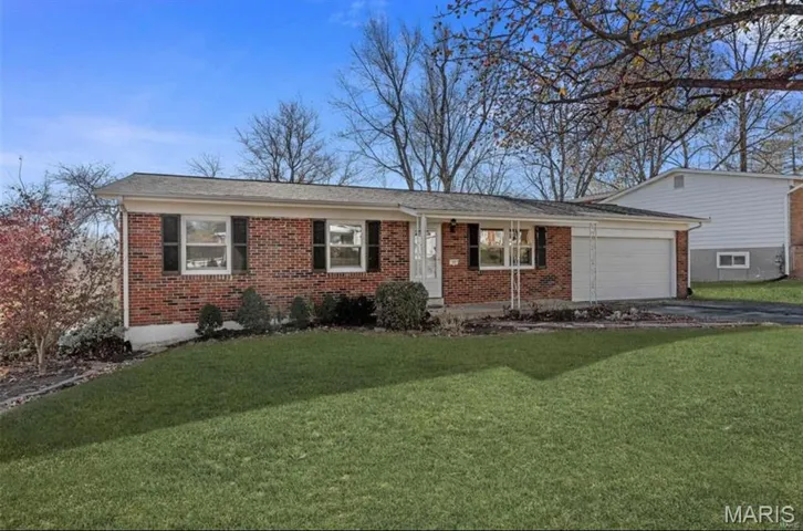 Ranch-style home with a front yard, brick siding, driveway, and an attached garage