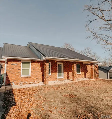 View of front of home featuring a metal roof and brick siding