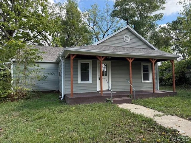 View of front facade featuring a shingled roof, a porch, and a front yard