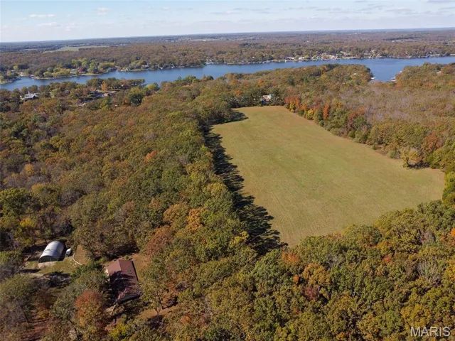 Aerial overview of property's location featuring a forest and a nearby body of water