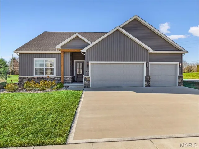 View of front facade with stone siding, concrete driveway, an attached garage, and a front yard *Virtually-Enhanced