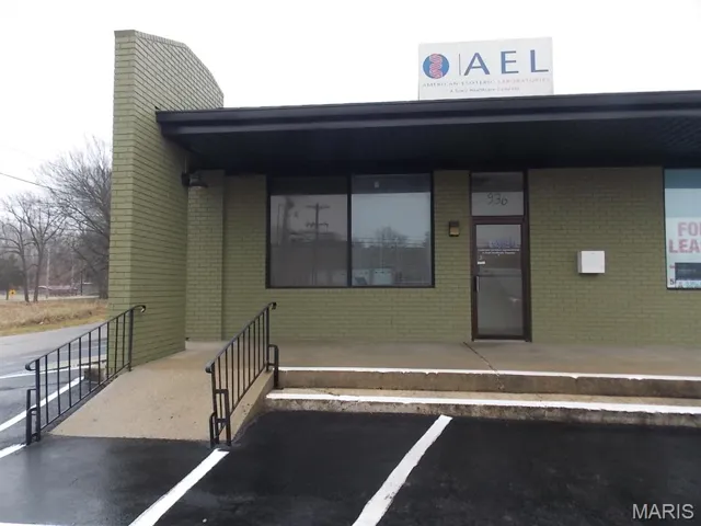 View of exterior entry featuring uncovered parking and brick siding