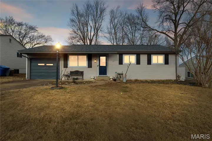 Twilight image of the ranch- style hoe with driveway, an attached garage, and  front lawn