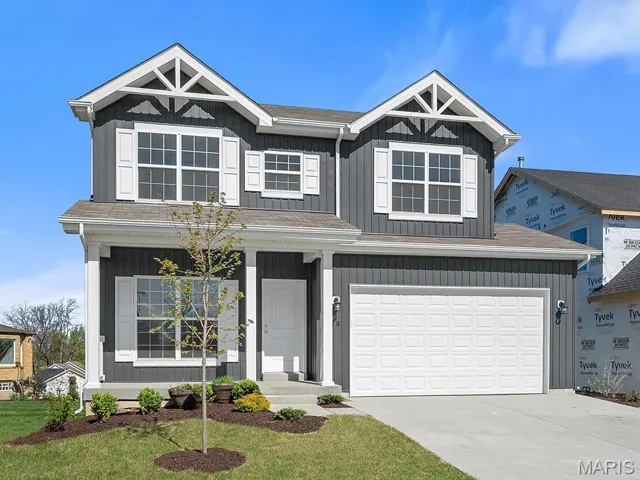View of front of home featuring driveway, an attached garage, a front yard, covered porch, and a shingled roof