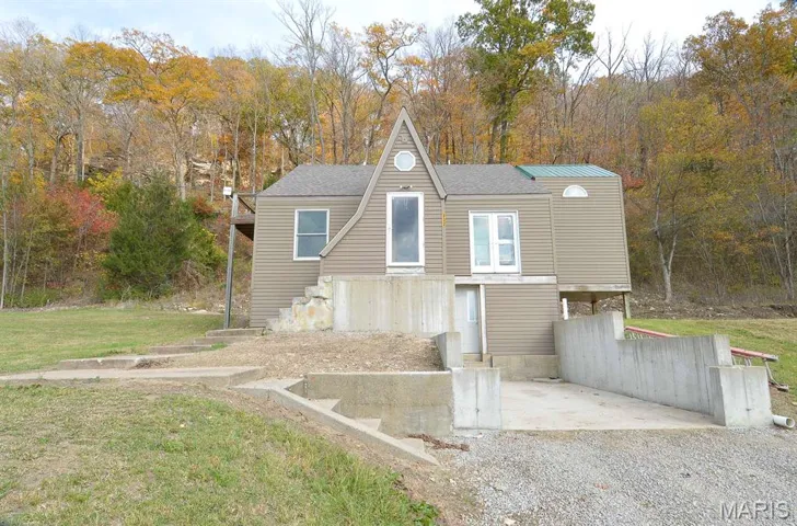View of front facade with a view of trees, roof with shingles, and a front yard
