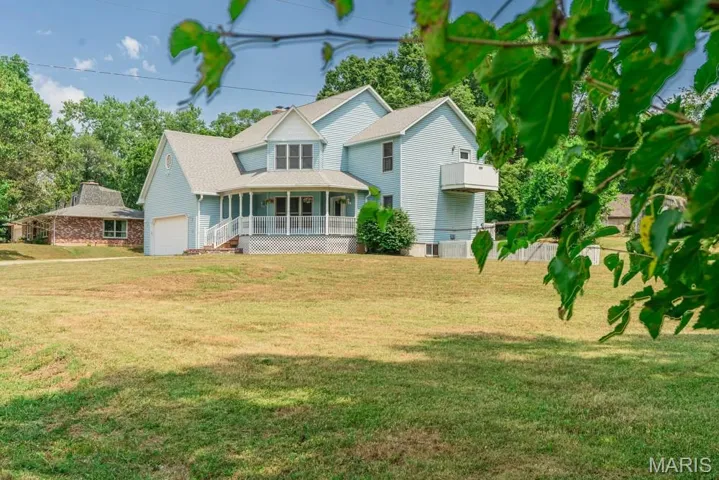 View of front of property with a front yard, covered porch, and roof with shingles