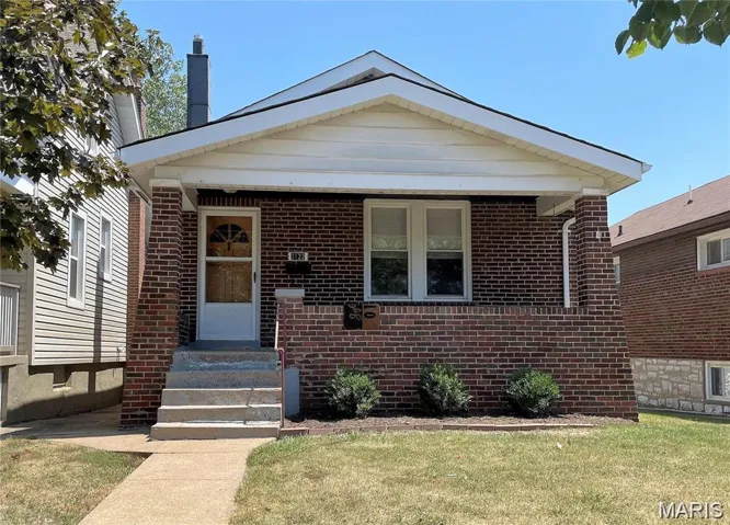 View of front of home with brick siding, a front lawn, and a porch
