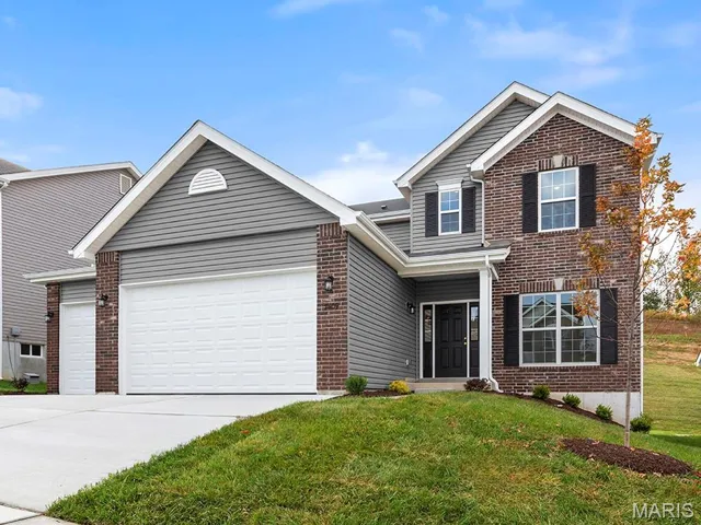 Traditional home with brick siding, driveway, a garage, and a front lawn