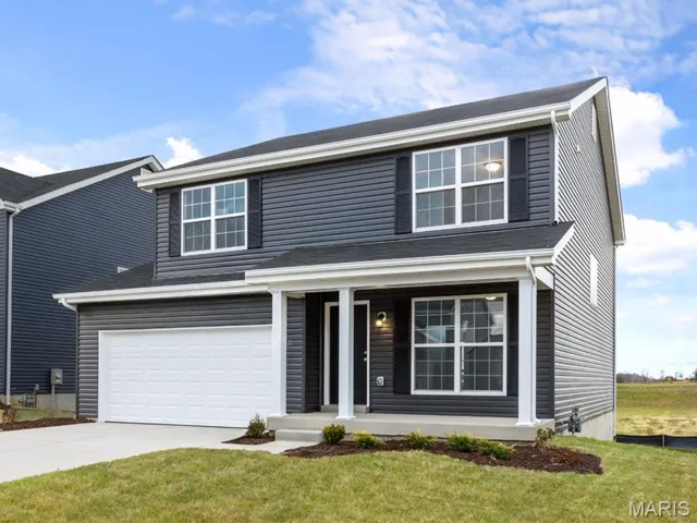 Traditional-style home with a porch, a garage, driveway, and a front yard