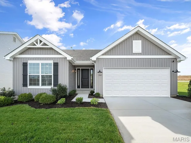 Single story home with driveway, a front yard, an attached garage, and board and batten siding