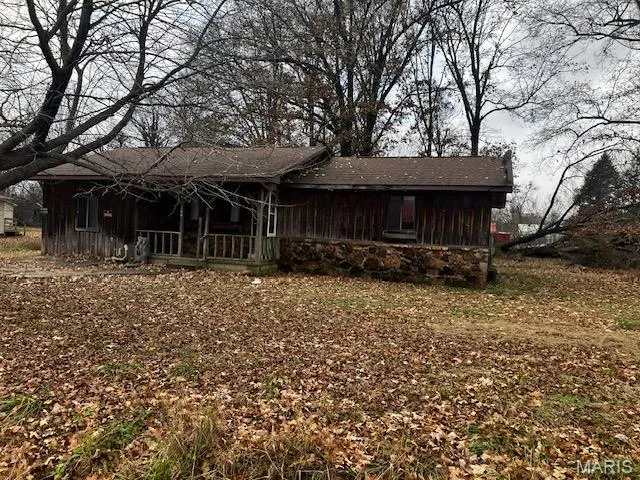 View of front of property with a porch, board and batten siding, stone siding, and roof with shingles