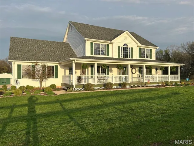 View of front of house featuring covered porch, roof with shingles, and a front yard