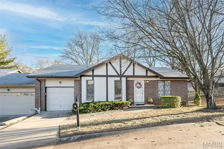 View of front facade featuring brick siding, driveway, a garage, and a shingled roof