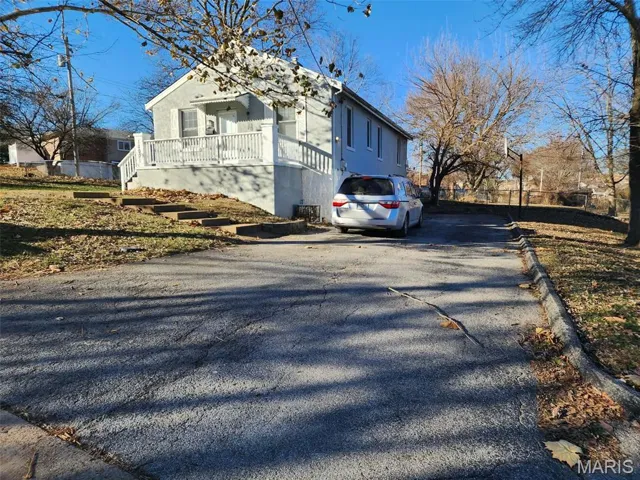 View of side of home with asphalt driveway and a porch