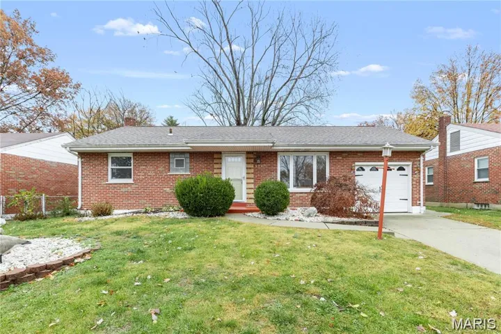 Ranch-style house featuring a garage, brick siding, a front lawn, driveway, and roof with shingles