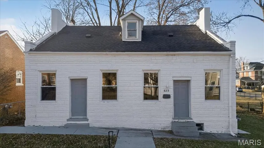 Back of house featuring stone siding and a shingled roof