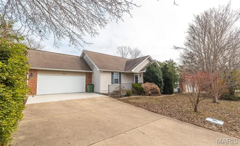 Ranch-style home featuring a shingled roof, concrete driveway, a garage, and brick siding