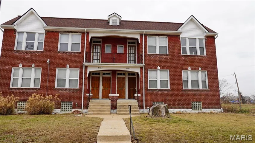 View of front facade with brick siding, a front lawn, and roof with shingles