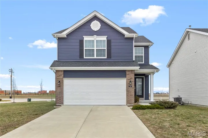 Traditional-style home featuring a garage, a shingled roof, concrete driveway, and brick siding