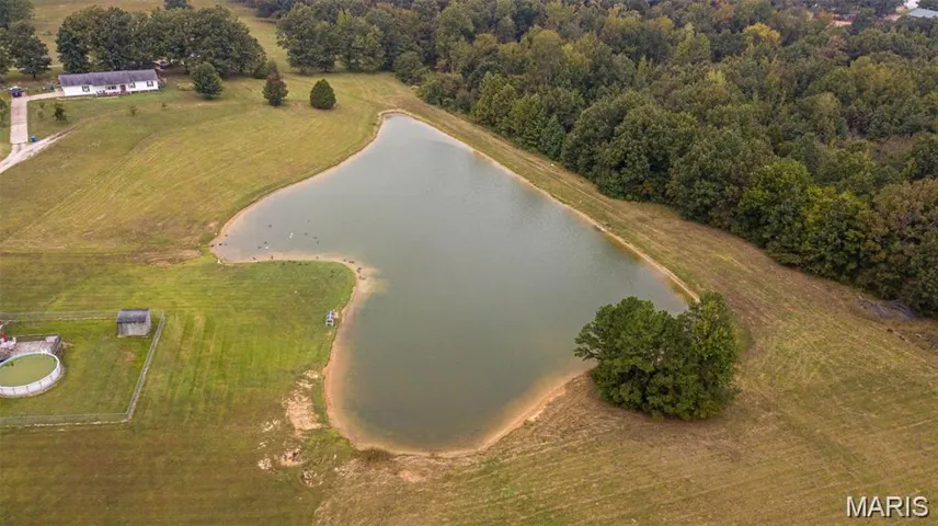 Aerial overview of property's location featuring a large body of water and a heavily wooded area