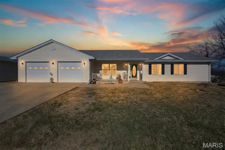 Ranch-style house with covered porch, a lawn, concrete driveway, an attached garage, and roof with shingles