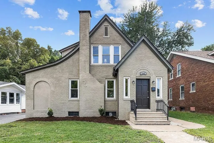 View of front of house featuring a chimney, a front yard, and brick siding
