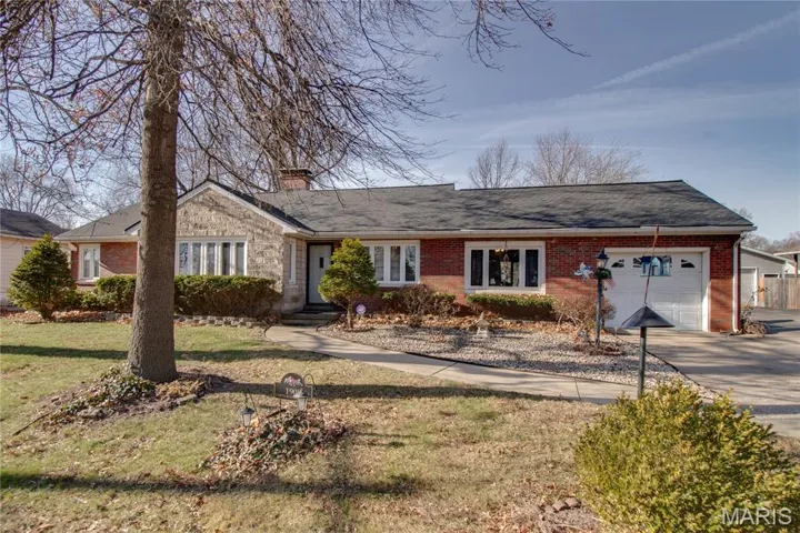 Ranch-style home with an attached garage, brick siding, a front lawn, and a chimney