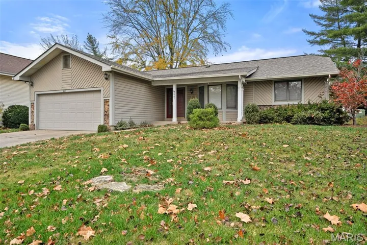 View of front of property with a front lawn, a garage, concrete driveway, stone siding, and roof with shingles
