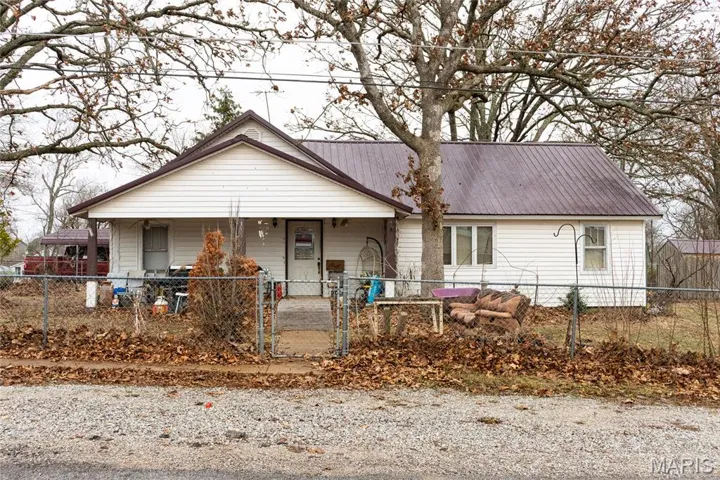 View of front of house with a fenced front yard, a gate, a metal roof, and a porch