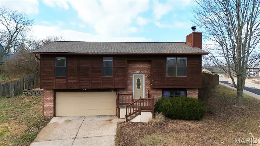 Split foyer home with brick and wood siding, roof is three years old, an attached garage, and concrete driveway.