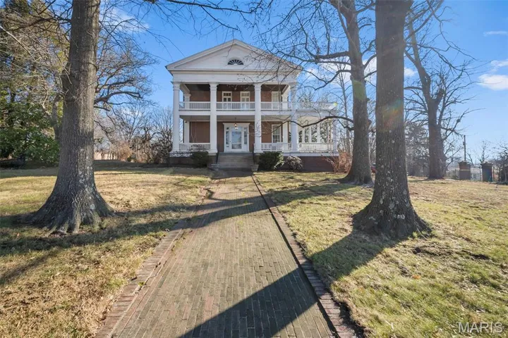 Neoclassical home featuring a porch and a front lawn