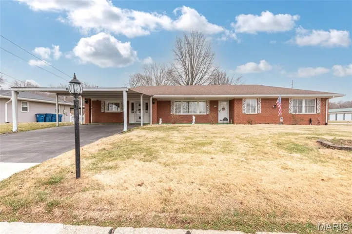 Ranch-style home featuring a front yard, brick siding, a carport, and driveway