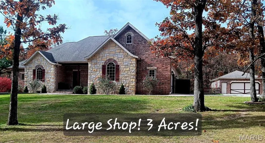 View of front facade featuring stone siding, brick siding, and a front lawn
