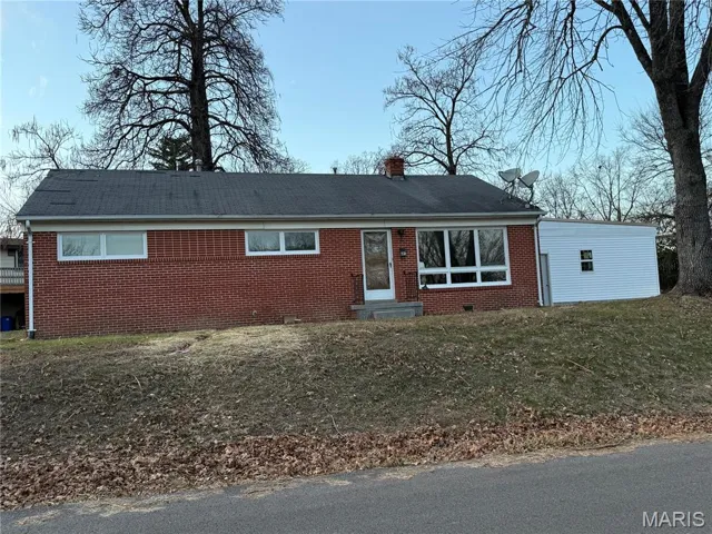 Ranch-style house featuring a front lawn, brick siding, entry steps, and a chimney