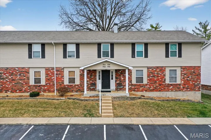 Colonial inspired home with uncovered parking, brick siding, and a chimney