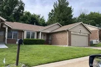 Ranch-style home featuring an attached garage, a front yard, brick siding, and driveway