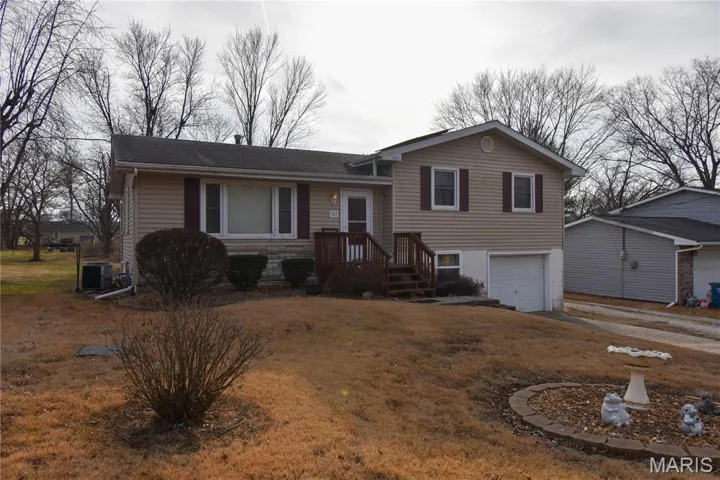 Split level home with a garage, driveway, roof with shingles, and a front yard