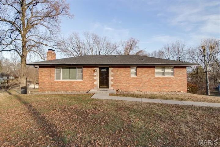 Single story home featuring brick siding, a chimney, a front lawn, and a shingled roof