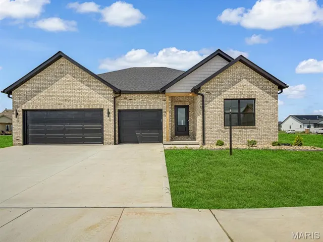 View of front of property with a front yard, concrete driveway, an attached garage, and brick siding