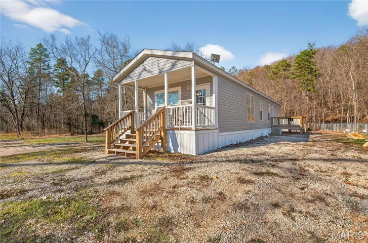 View of front of property with a forest view and covered porch