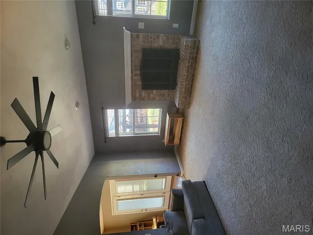 Carpeted living area with a fireplace, arched walkways, and ceiling fan
