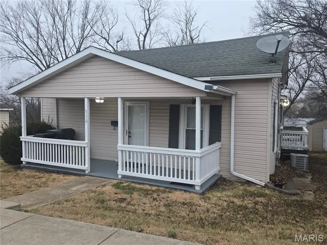 Bungalow-style home featuring roof with shingles, a porch, and a front yard