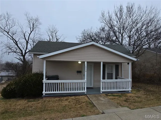 Bungalow-style home featuring covered porch, roof with shingles, and a front yard