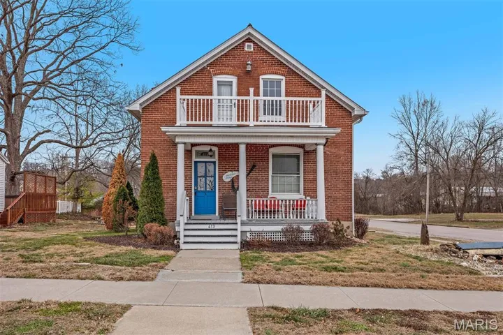 View of front of house featuring brick siding, covered porch, and a balcony