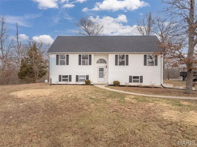 Raised ranch featuring a front lawn and a shingled roof